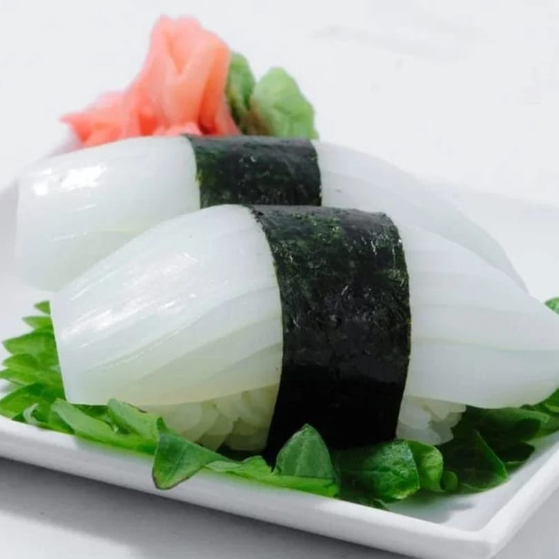 Two squid nigiri sushi pieces with pickled ginger and wasabi on a white plate.